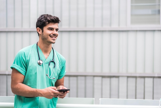 Doctor masculino usando teléfono inteligente al aire libre