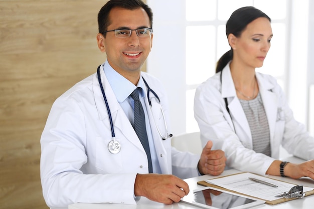 Doctor de mediana edad llenando documentos médicos o recetas con su colega