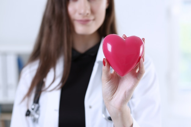 Doctor en medicina femenina manos sosteniendo corazón rojo