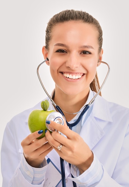 Foto doctor en medicina mujer examinando manzana con estetoscopio