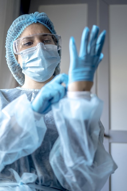 Foto doctor en medicina poniéndose guantes azules protectores