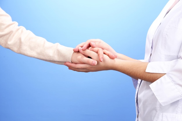 Doctor en medicina sosteniendo la mano del paciente sobre un fondo claro