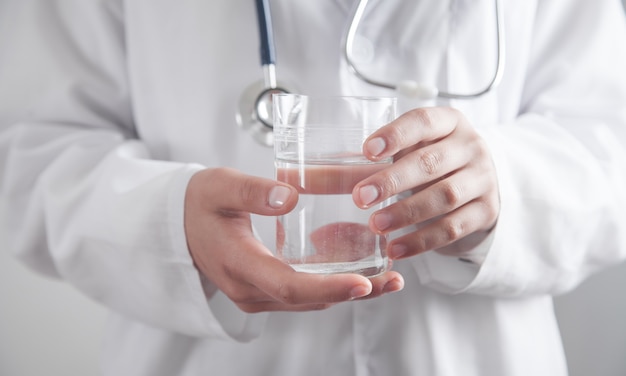 Doctor en medicina sosteniendo un vaso de agua.