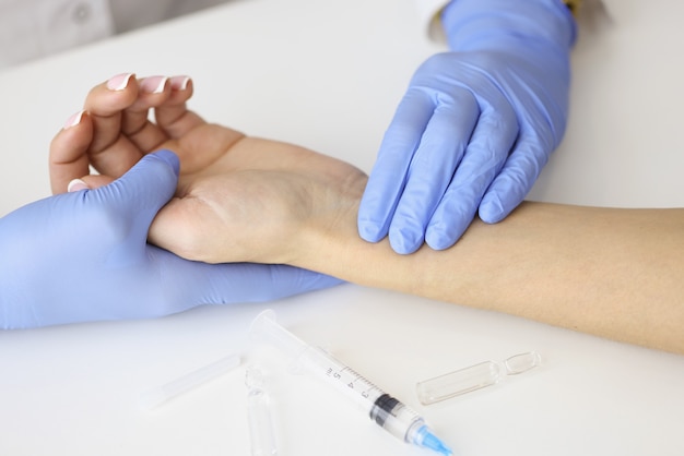 Foto doctor midiendo el pulso en el antebrazo del paciente cerca de la jeringa vacía y el primer de la medicación