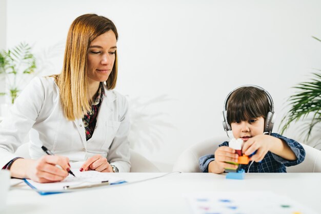 El doctor mira a un niño jugando con juguetes en la mesa en el hospital