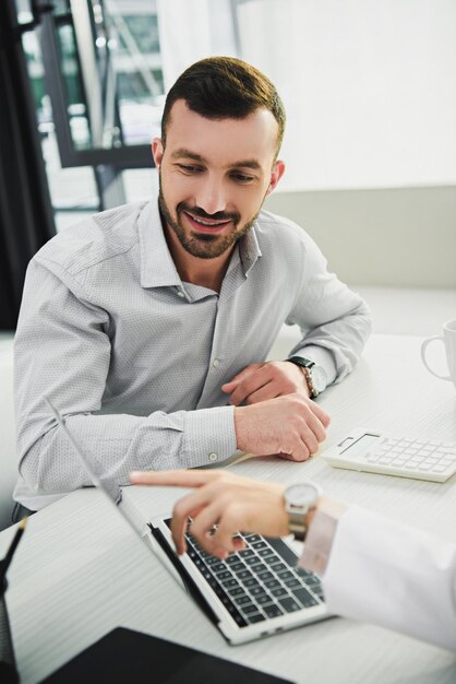 Doctor mostrando algo en la computadora portátil a un cliente masculino en la oficina