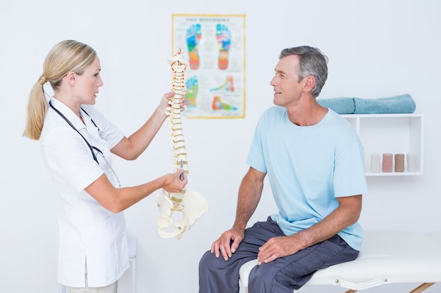 Doctor mostrando la columna vertebral anatómica a su paciente