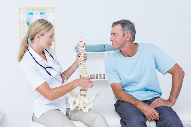 Doctor mostrando la columna vertebral anatómica a su paciente