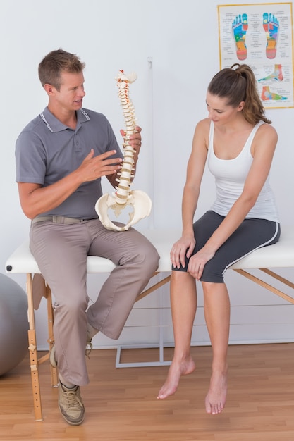 Doctor mostrando la columna vertebral anatómica a su paciente.