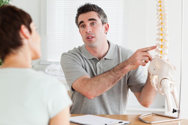 Doctor mostrando a un paciente una parte de una columna vertebral