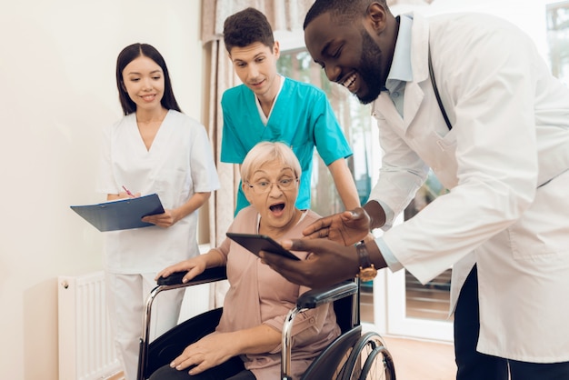 El doctor muestra algo en la tableta a un paciente anciano.