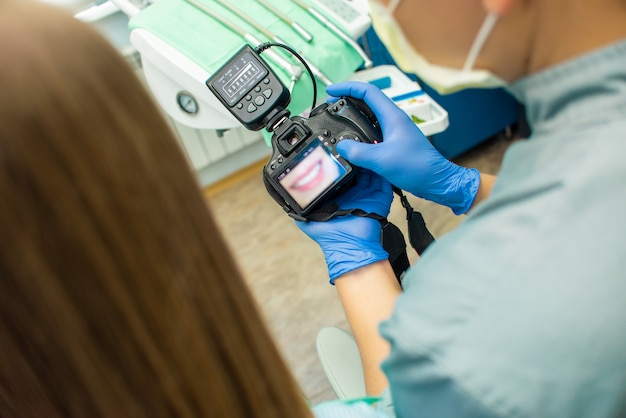 Foto doctor muestra a niña una foto de sus dientes en cámara