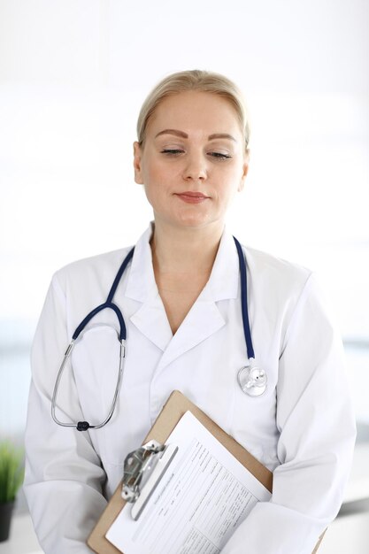 Doctor mujer adulta de pie directamente en la oficina del hospital, retrato. Perfecto servicio médico en clínica. Conceptos de medicina y salud.