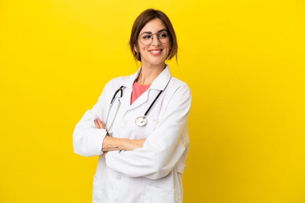 Doctor mujer aislada sobre fondo amarillo con los brazos cruzados y feliz