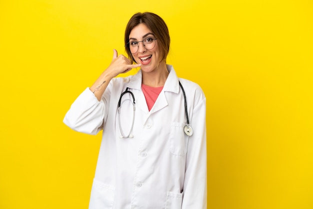 Doctor mujer aislada sobre fondo amarillo haciendo gesto de teléfono. Llámame señal