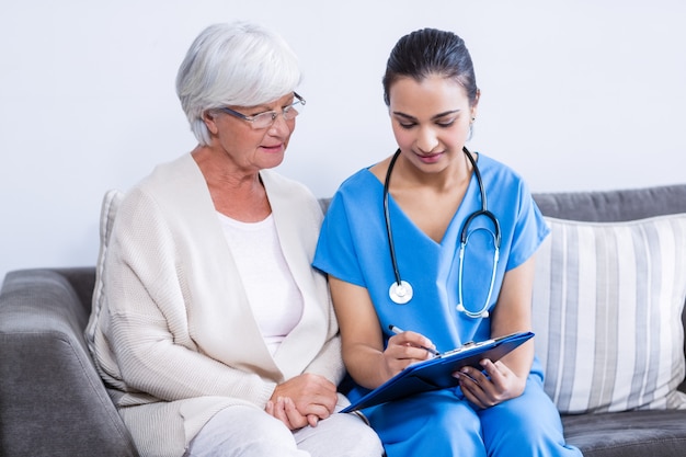 Doctor y mujer mayor discutiendo en portapapeles