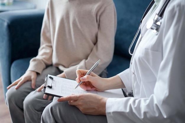 Doctor mujer y niño niño paciente en casa examen médico. El pediatra llenando el formulario médico en el portapapeles, de cerca. Medicina, conceptos sanitarios