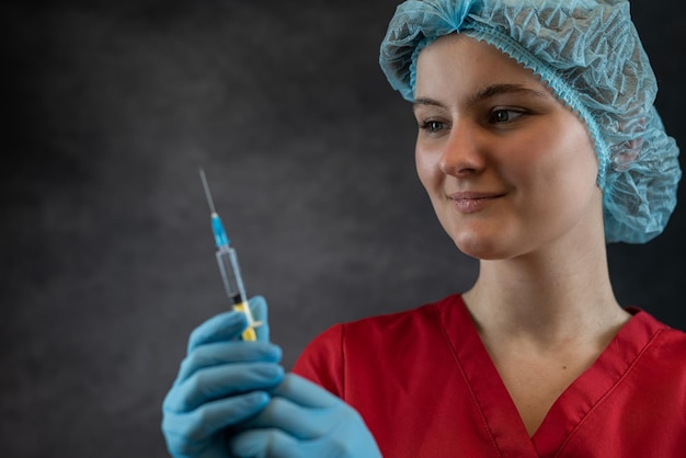 Foto doctor mujer vestida con uniforme médico rojo guanteros sombrero máscara con jeringa con líquido aislado