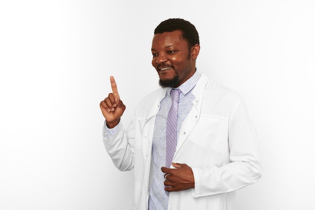 Un doctor negro feliz con barba pequeña con bata blanca y camisa brillante tiene una idea de fondo blanco