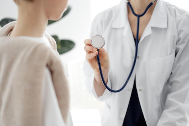 Doctor y un niño paciente. El médico sostiene un estetoscopio y está listo para examinar al niño. Concepto de salud perfecto en medicina.