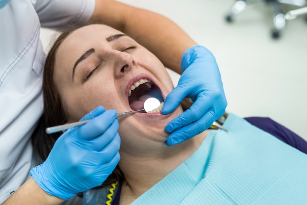 Doctor en odontología examinando los dientes del paciente con espejo