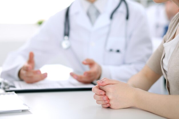 El doctor y el paciente están discutiendo algo, apenas las manos en la tabla.