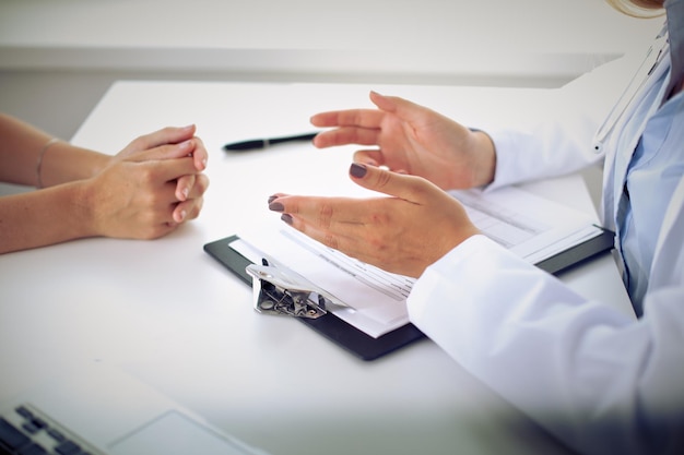 El doctor y el paciente están discutiendo algo, apenas las manos en la tabla.