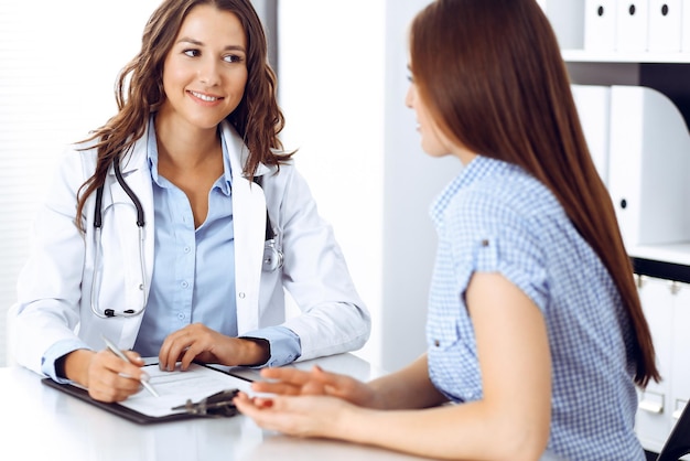 Foto doctor y paciente hablando mientras están sentados en el escritorio. el médico discutiendo un estilo de vida saludable. concepto de atención médica, medicina y servicio al paciente.