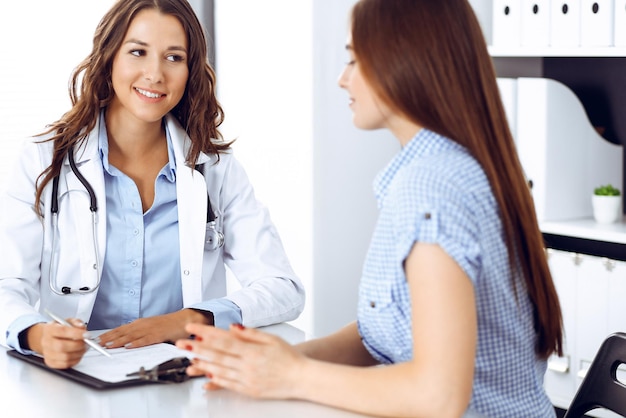 Foto doctor y paciente hablando mientras están sentados en el escritorio. el médico discutiendo un estilo de vida saludable. concepto de atención médica, medicina y servicio al paciente.