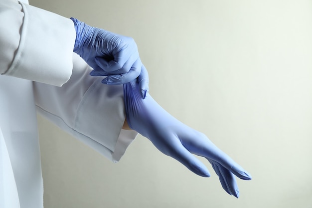 Foto doctor poniendo guantes médicos sobre fondo gris claro aislado