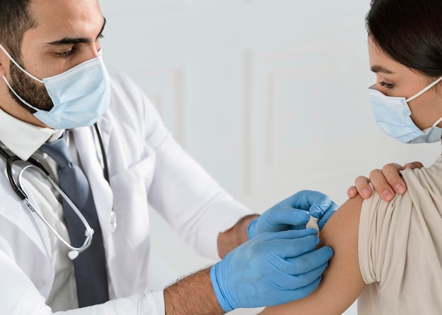 Doctor poniendo un vendaje en el brazo de una mujer