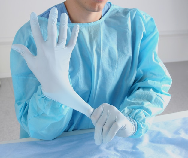 Doctor poniéndose guantes estériles.