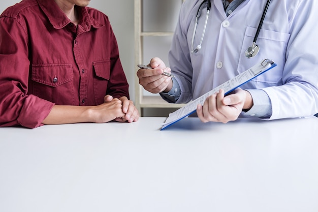 Foto doctor que consulta al paciente que discute algo y recomienda métodos de tratamiento, presentando resultados en el informe