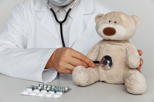 Doctor que controla los latidos del corazón del oso de peluche en el hospital. Concepto de pediatra.