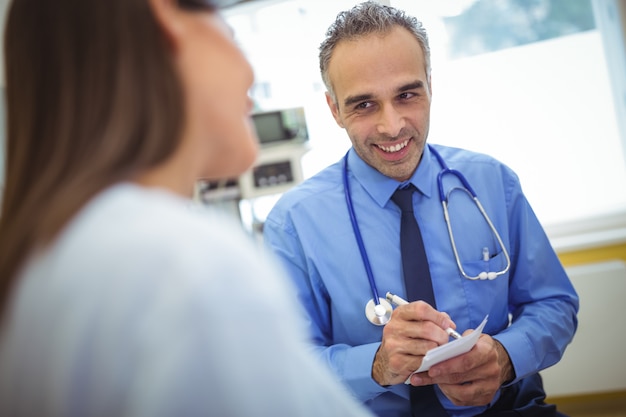 Doctor que interactúa escribiendo en papel mientras consulta al paciente