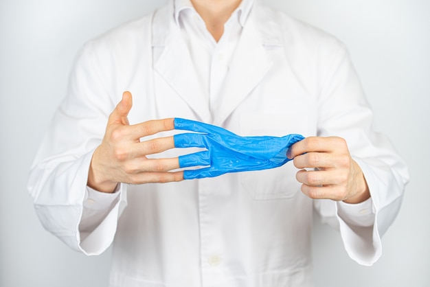 un doctor que se quita los guantes de látex azul