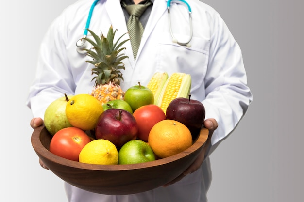 El doctor que sostiene la cesta clasifica las frutas y verduras frescas