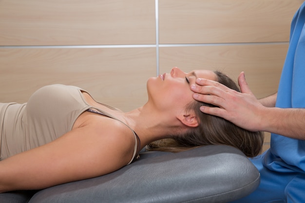 Doctor en reflexología facial manos en rostro de mujer