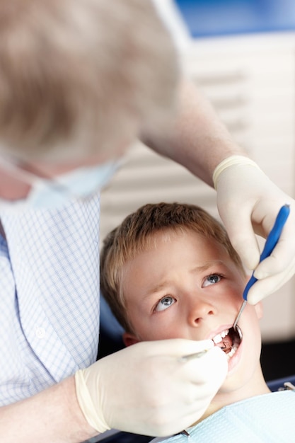 Doctor revisando los dientes de los niños Vista de ángulo alto del doctor revisando los dientes de los niños en la clínica