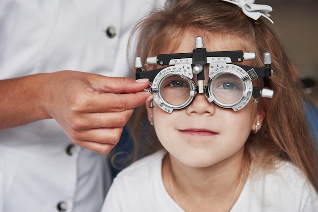 Doctor revisando la vista de la niña y afinando el foróptero