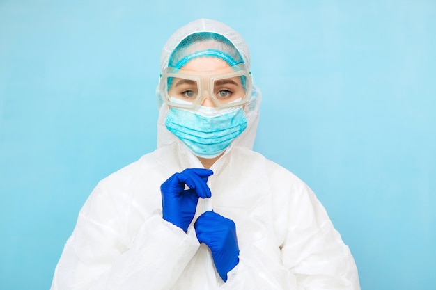 Doctor en ropa protectora. La doctora usa un mono protector, una máscara y guantes azules. epidemia covid-2019. coronavirus. Retrato de primer plano del médico enmascarado.