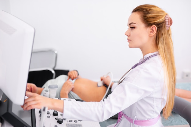 Doctor rubio joven que trabaja en la máquina del ultrasonido en nueva clínica