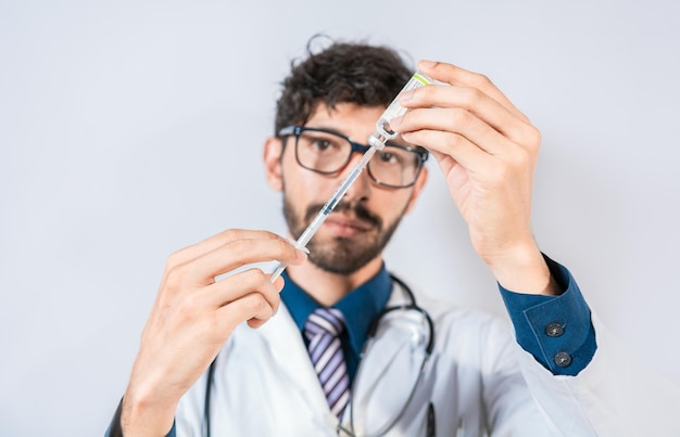 Doctor sacando medicina de un vial aislado Joven doctor sacando medicina de un vial con espacio de copia Concepto de doctor con antídoto de enfermedad