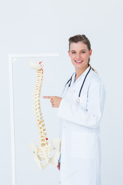 Doctor señalando una columna vertebral anatómica