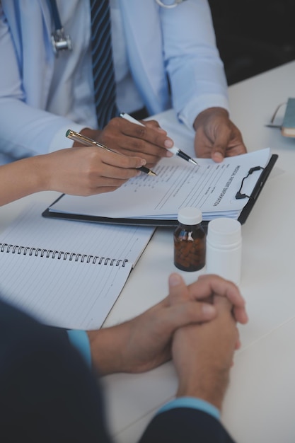 Doctor sentado en el escritorio y escribiendo una receta para su paciente