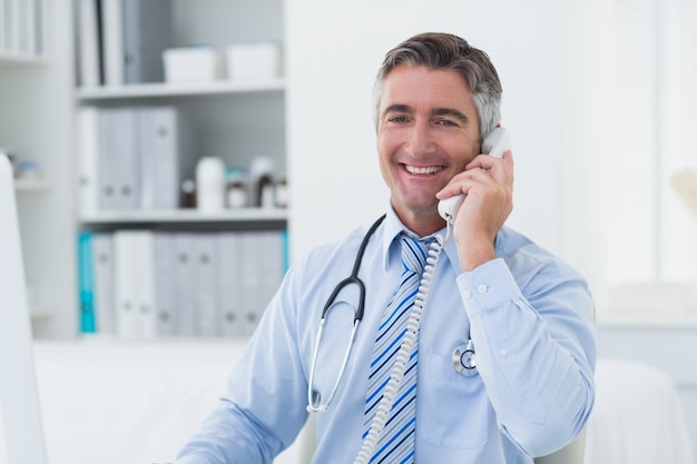 Doctor de sexo masculino confidente que usa el teléfono en clínica
