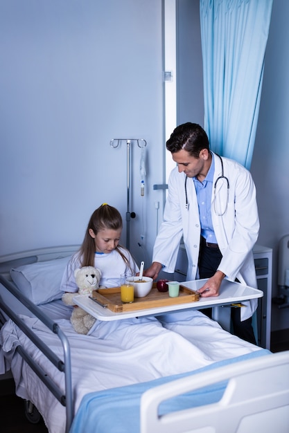 Doctor sirviendo el desayuno a la niña