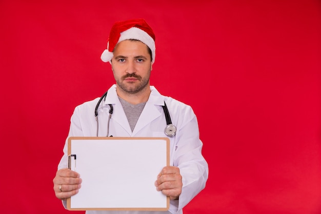 Doctor en sombrero de Santa Claus con portapapeles en blanco