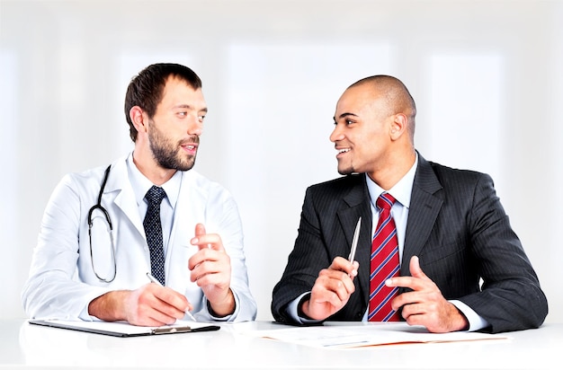 Doctor sonriendo con paciente masculino sentado en la mesa