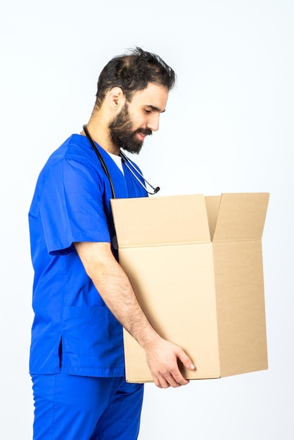 Doctor sonriendo y sosteniendo una caja sobre fondo blanco Studio